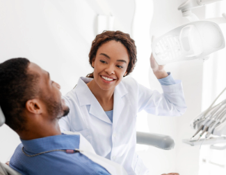 Female dentist turning on lamp before tratment mobile